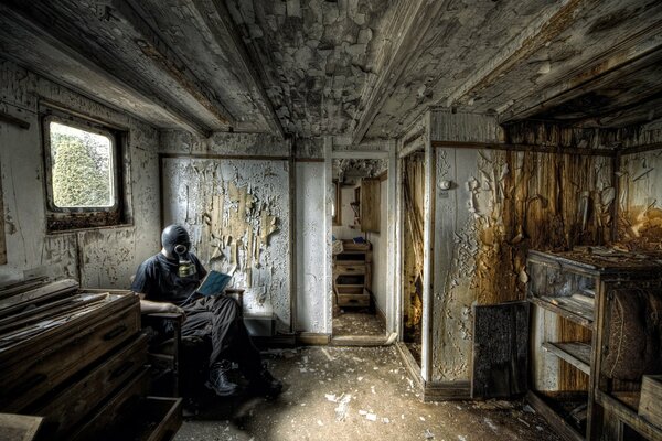 A man in a gas mask reads a book