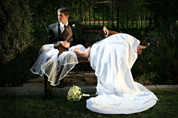 The bride and groom are resting on a bench