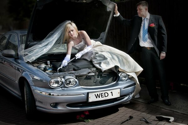 A girl in a wedding dress repairs a car