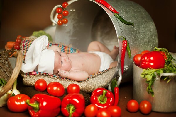 Bebé cocinero entre pimientos rojos