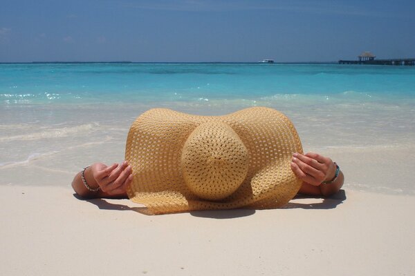 Ragazza in un grande cappello in riva al mare