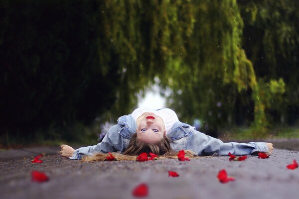 La jeune fille se trouve sur la route au milieu des pétales de fleurs