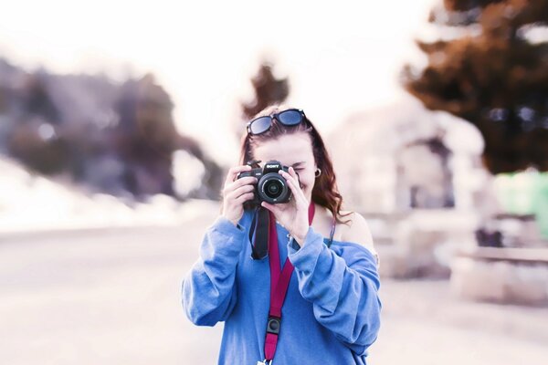 Una ragazza in un maglione blu con gli occhiali sulla testa guarda nell obiettivo di macchina fotografica