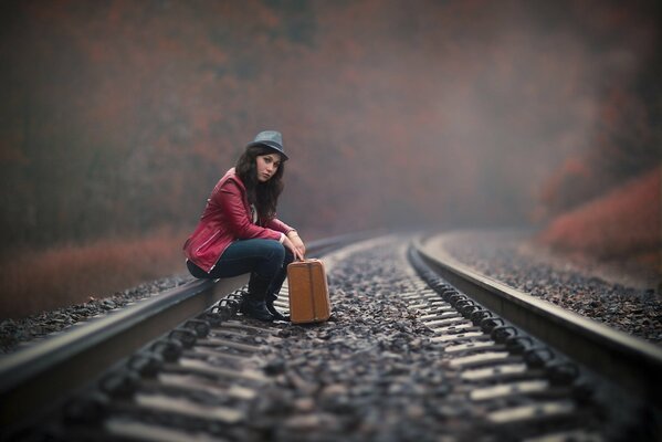 La jeune fille attend avec des valises sur les rails