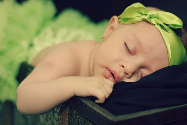 Dulce niña con un arco verde durmiendo