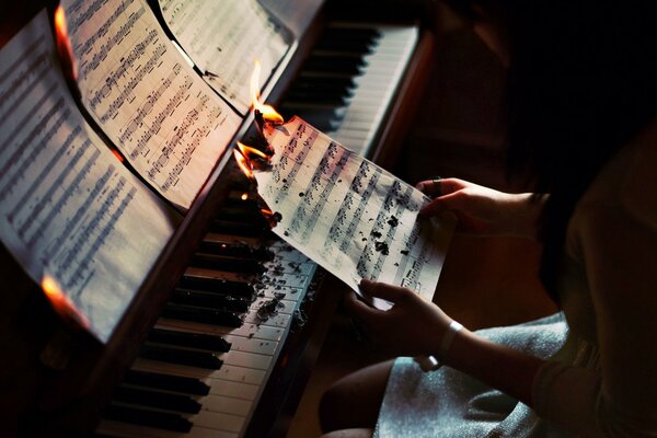 La ragazza si siede al pianoforte e brucia un foglio con le note