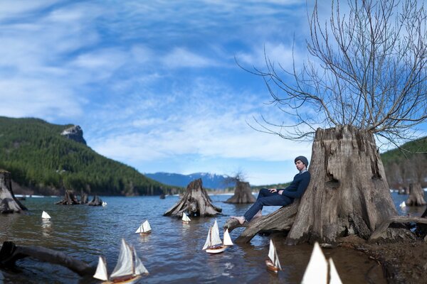 Un gars assis appuyé contre l arbre et regarde les bateaux