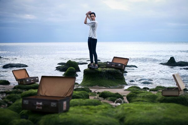 A guy and a lot of open suitcases on the background of the sea