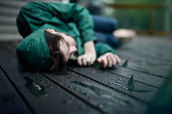 A man is lying on the floor among wet boats