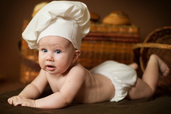 Bambino in un cappello da cuoco su uno sfondo di cestini
