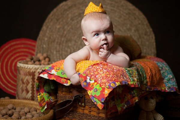 Le bébé sur la couverture réfléchi avec un doigt dans la bouche