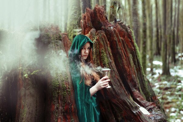 A witch with a mystical glass in the forest