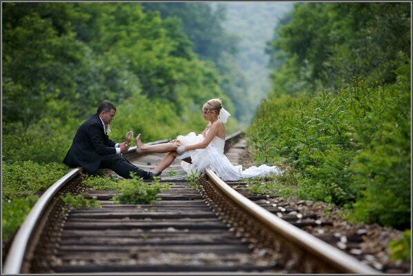 La mariée et le marié ont décidé de faire une belle prise de vue en forêt sur des rails de train