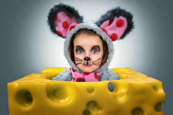 A girl in a mouse costume climbs out of a piece of cheese