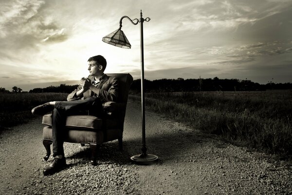 A guy in a classic suit is sitting in a chair on the street