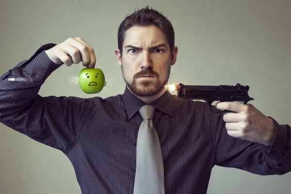 A man with a gun and an apple. Staged photo