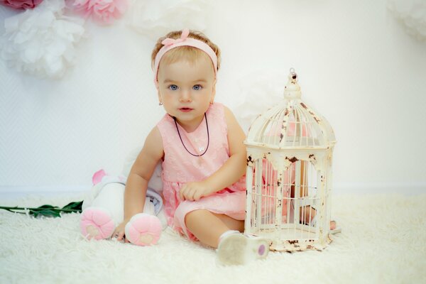 A girl in a pink dress with a bird cage