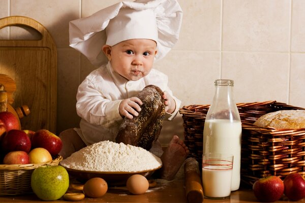 A baby cook surrounded by food