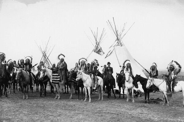 A lot of Indians on the background of wigwams