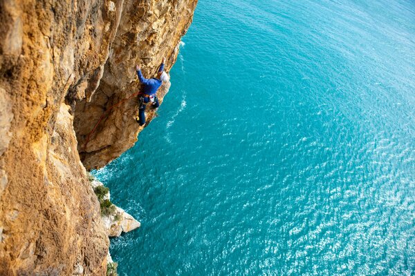 Scalatore che si arrampica su una roccia sopra il mare