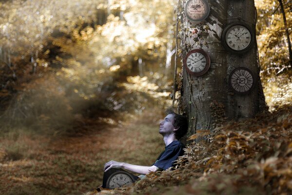 Nella foresta, un ragazzo con un orologio si siede vicino a un albero