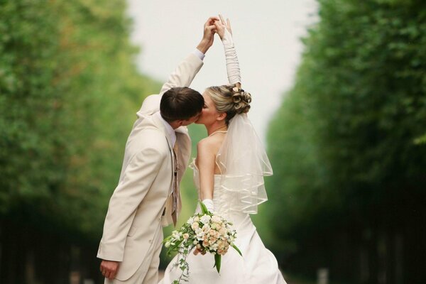 Zdjęcie ślubne nowożeńców całujących się trzymających się za rękę