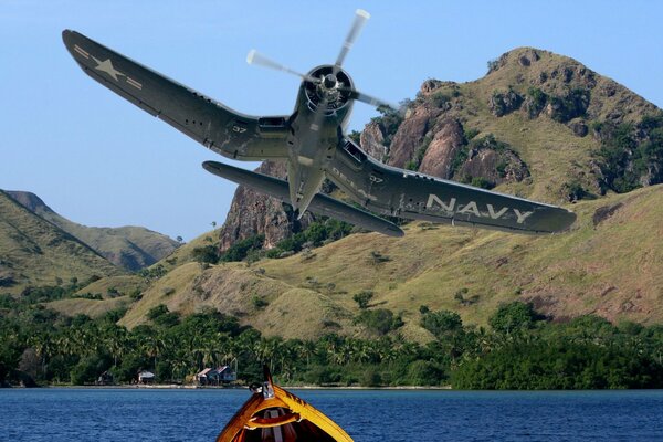 The plane is flying over the water into the mountains