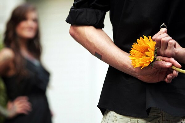 A guy with a flower and a ring proposes to a girl