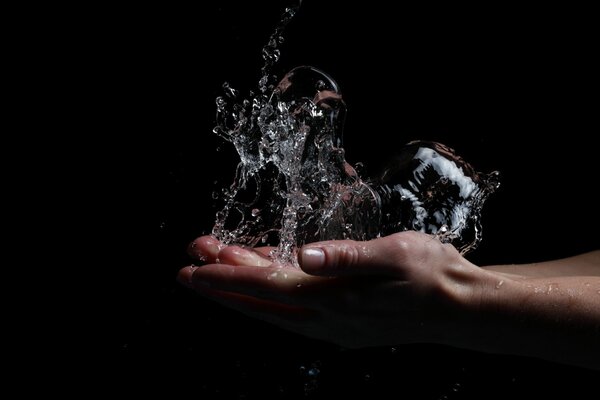 Hand with water splashes on a black background