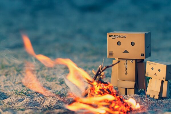 A pair of cardboard danbo men warming themselves by the fire