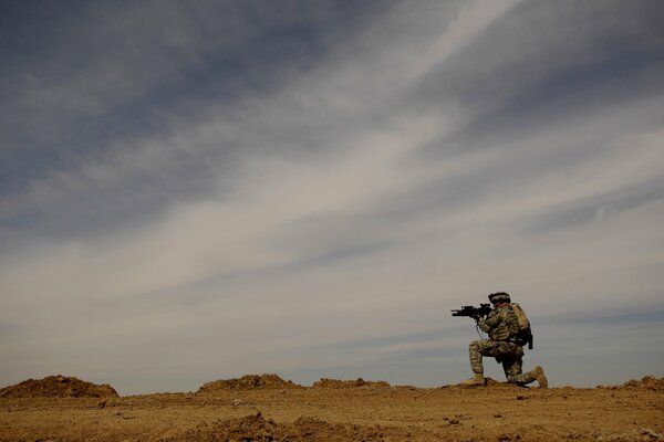 A soldier in the desert on the ground and rocks