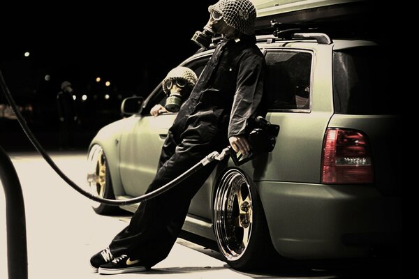 A funny gas station attendant in a gas mask leaned against the car door