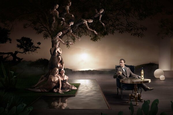 An art man sits at a table and looks at women in a tree