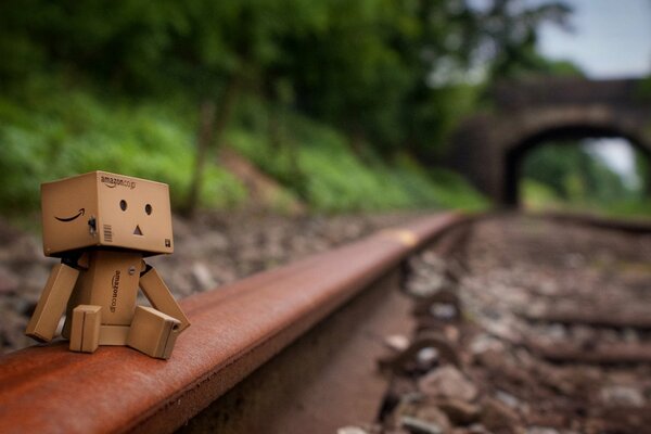 Danbo KARTONOWY człowiek siedzący na torach oddalającej się w dal kolei