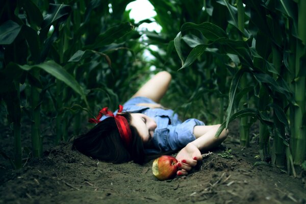 Chica con una manzana tendida en un campo