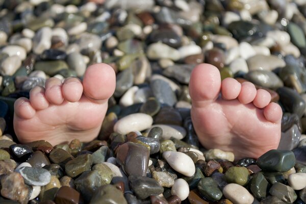Buried feet in the pebbles stick out only fingers