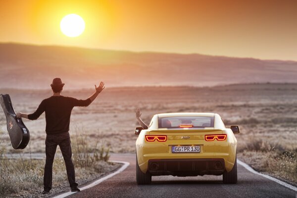 Ein Mann mit einer Gitarre auf der Straße in der Nähe eines wegfahrenden Autos