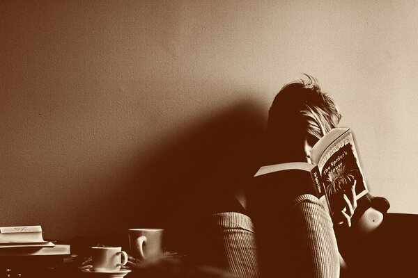 Una foto acogedora leyendo a un hombre con una taza de kofk