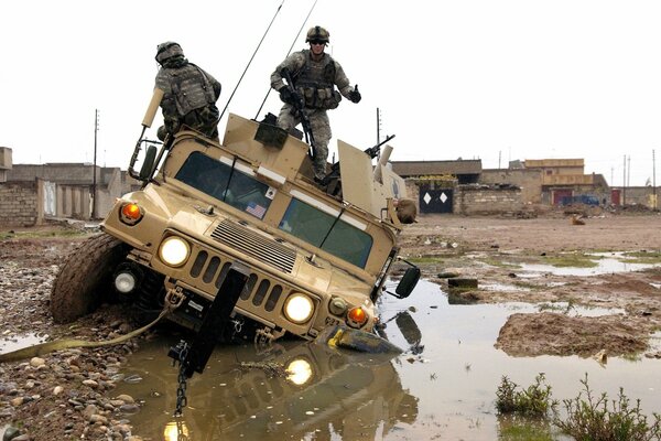 A military jeep is pulled out of a puddle