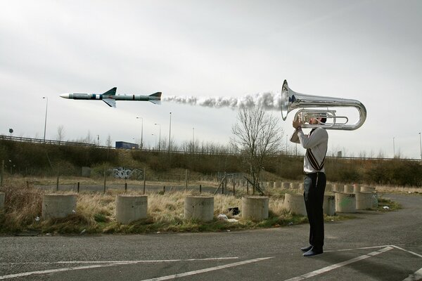 The guy blows into the pipe from which the rocket flies out