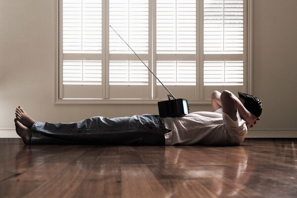 Un homme allongé sur le sol à regarder la télévision