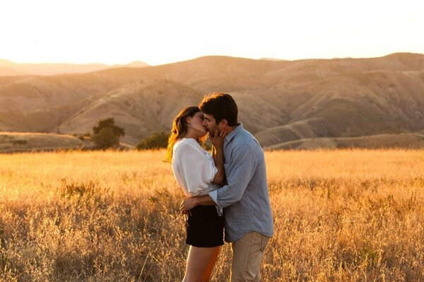 A young couple kissing in the middle of a wheat field