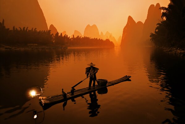 Fisherman in a boat on the background of mountains