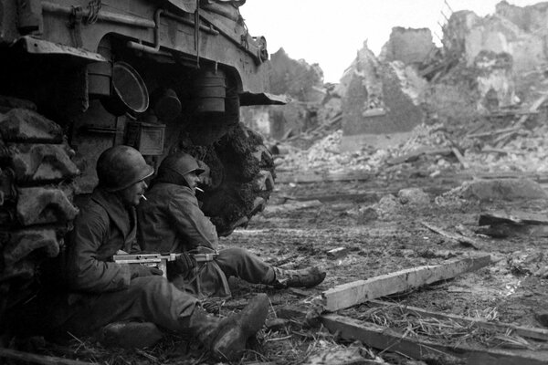 Soldados sentados cerca de un tanque con armas en la mano