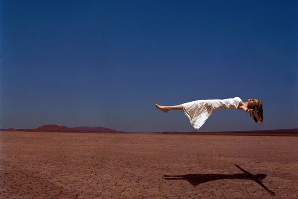 Ragazza che vola sopra il deserto contro il cielo