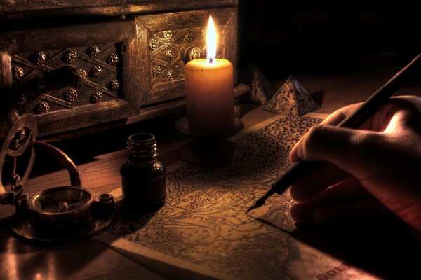 Człowiek pisze piórem w świetle świecy