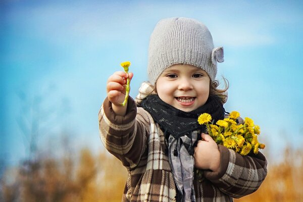 A girl with a bouquet of the first dandelions