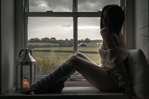 La jeune fille dans les guêtres sur la fenêtre