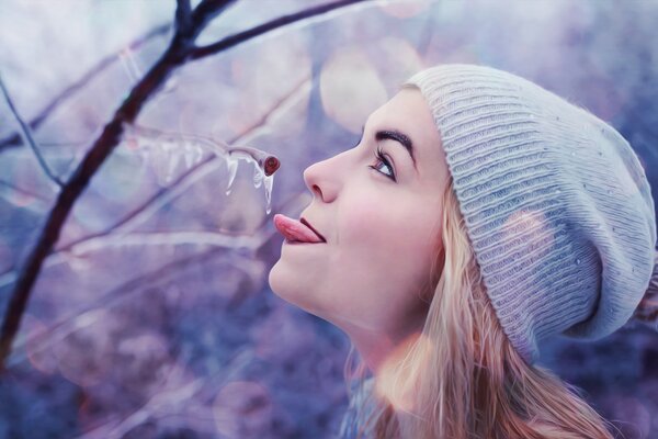 The girl stuck her tongue out to the ice on the branch