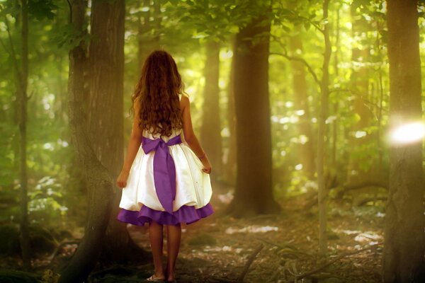 Ein Mädchen in einem schönen Kleid steht mit dem Rücken im Wald